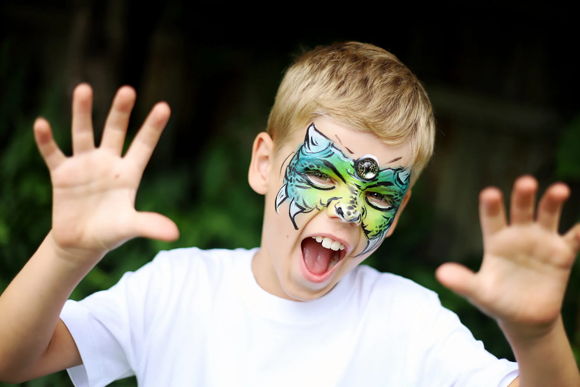 A boy roaring in a dragon face paint design